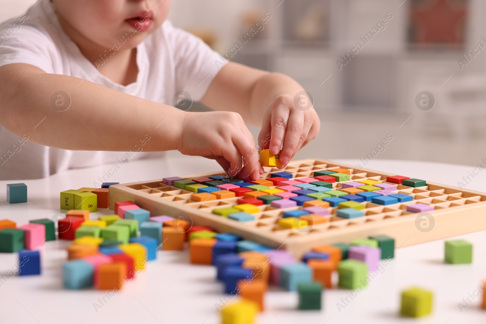 Photo of Motor skills development. Little boy playing with Times table tray indoors, closeup