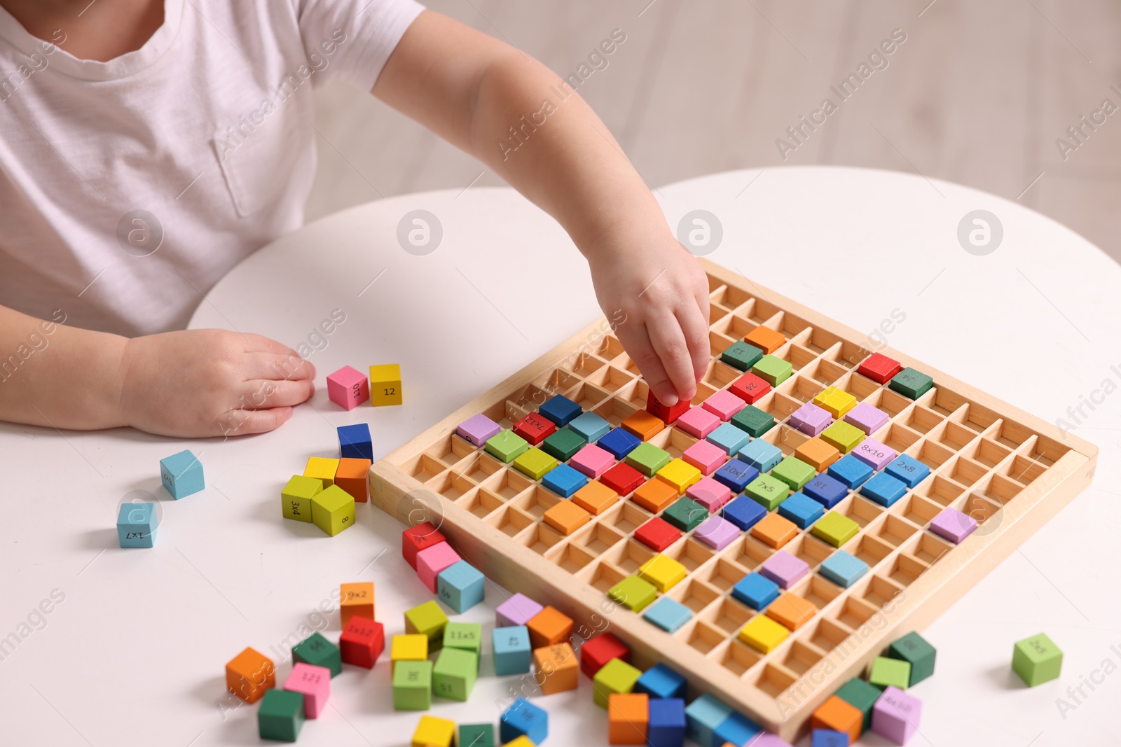 Photo of Motor skills development. Little boy playing with Times table tray indoors, closeup