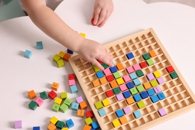 Motor skills development. Little boy playing with Times table tray at white table, above view