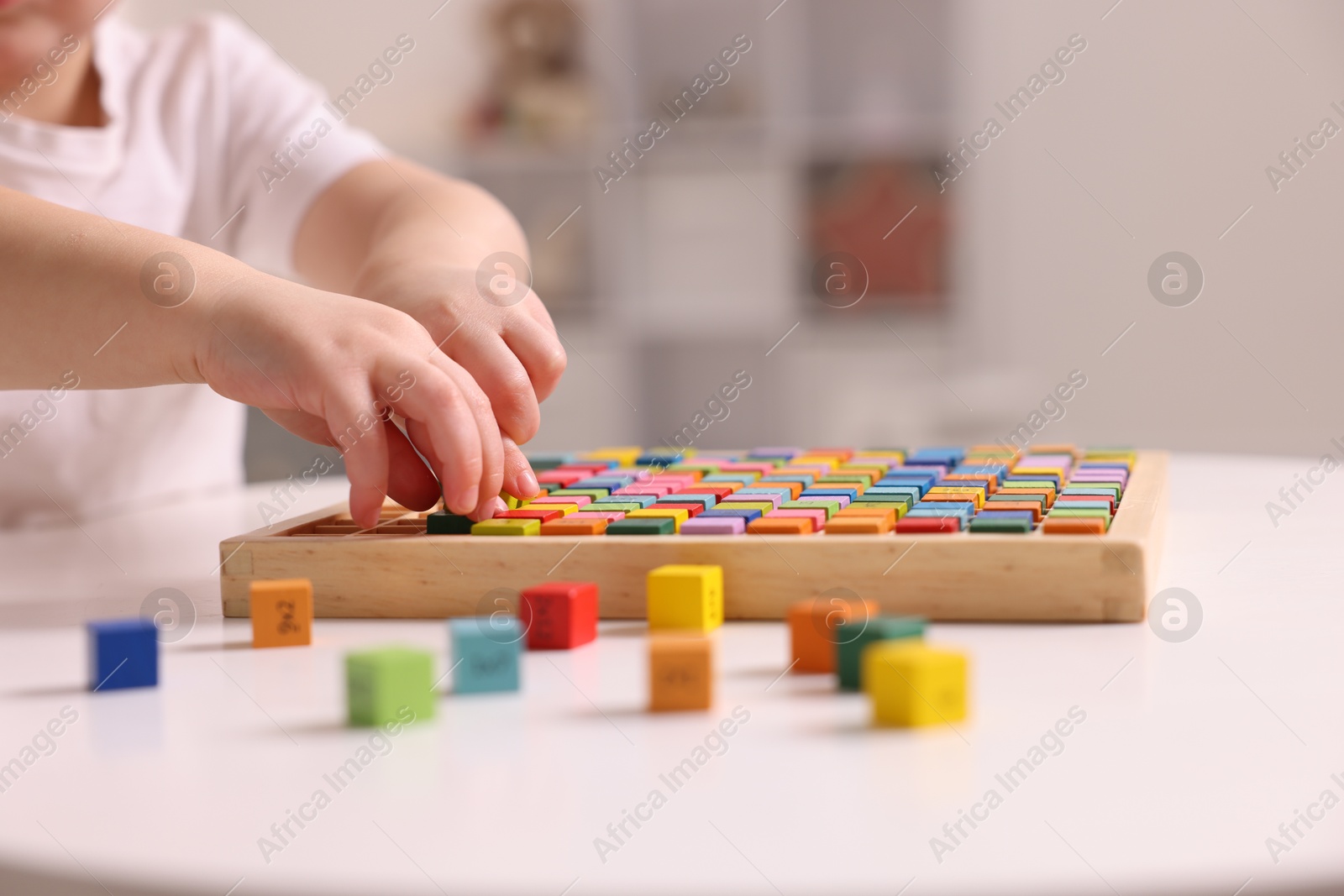 Photo of Motor skills development. Little boy playing with Times table tray indoors, closeup