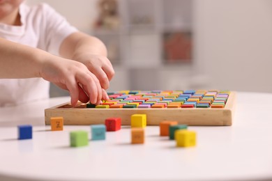 Motor skills development. Little boy playing with Times table tray indoors, closeup