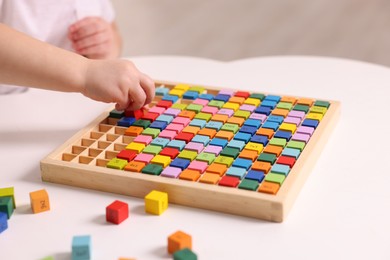 Photo of Motor skills development. Little boy playing with Times table tray indoors, closeup