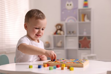 Photo of Motor skills development. Little boy playing with Times table tray indoors