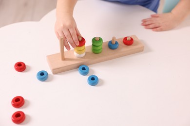 Photo of Motor skills development. Little boy playing with stacking toy at white table indoors, closeup