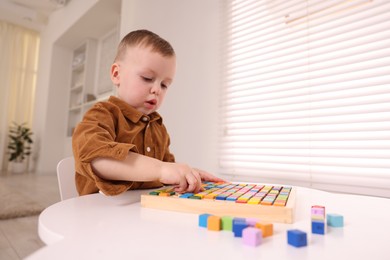 Photo of Motor skills development. Little boy playing with Times table tray indoors