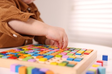 Motor skills development. Little boy playing with Times table tray indoors, closeup