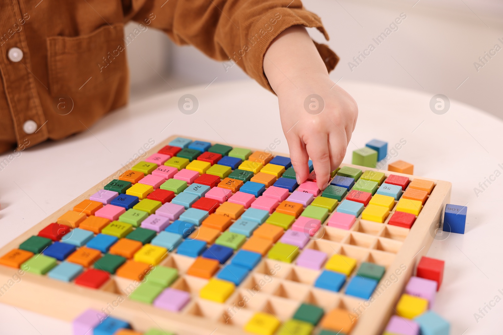 Photo of Motor skills development. Little boy playing with Times table tray indoors, closeup