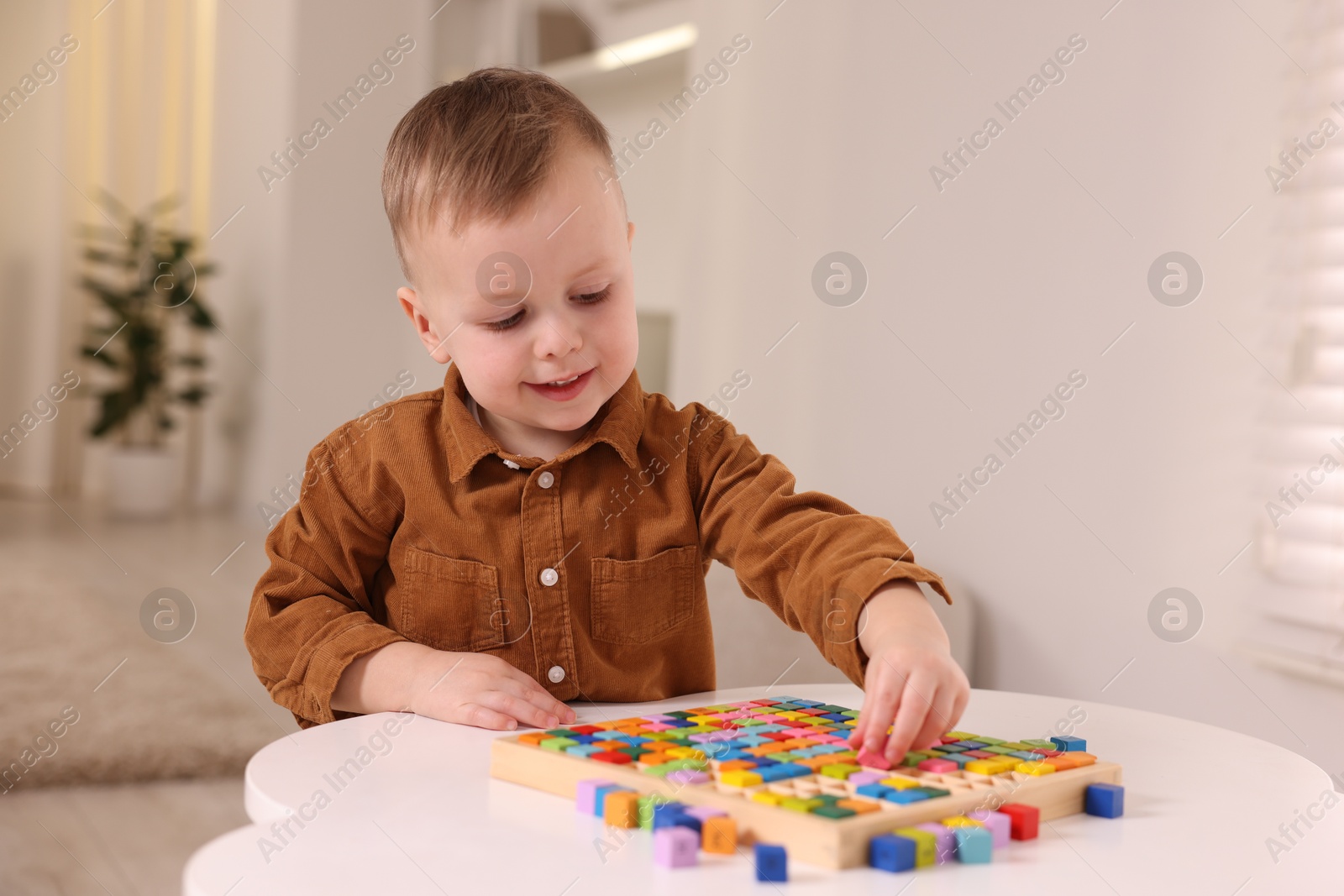 Photo of Motor skills development. Little boy playing with Times table tray indoors