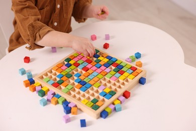 Photo of Motor skills development. Little boy playing with Times table tray indoors, closeup