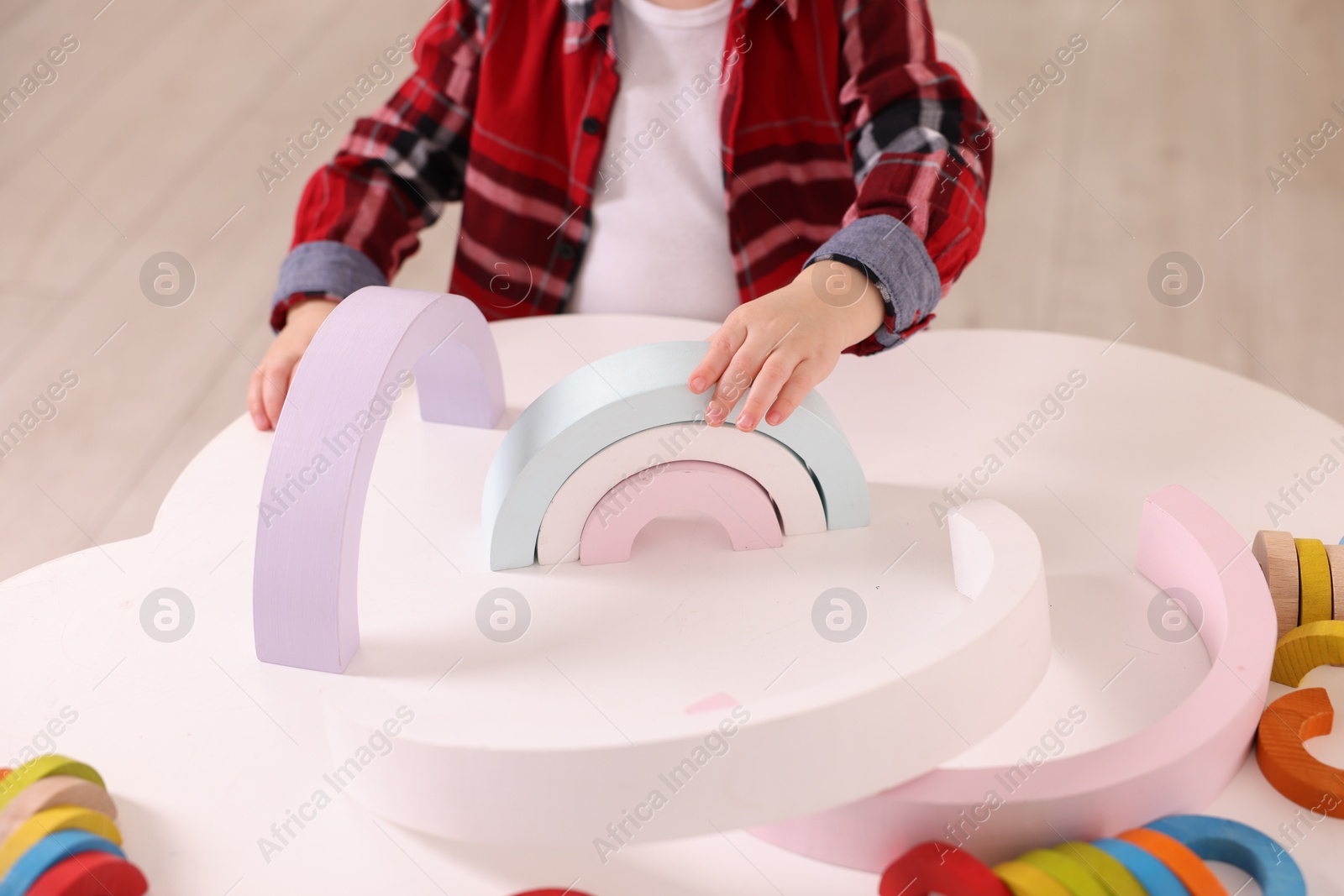 Photo of Motor skills development. Little boy playing with toys at white table indoors, closeup