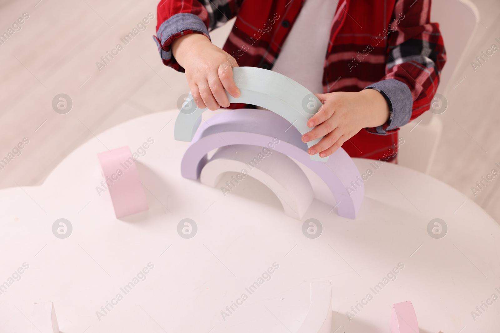 Photo of Motor skills development. Little boy playing with toys at white table indoors, closeup