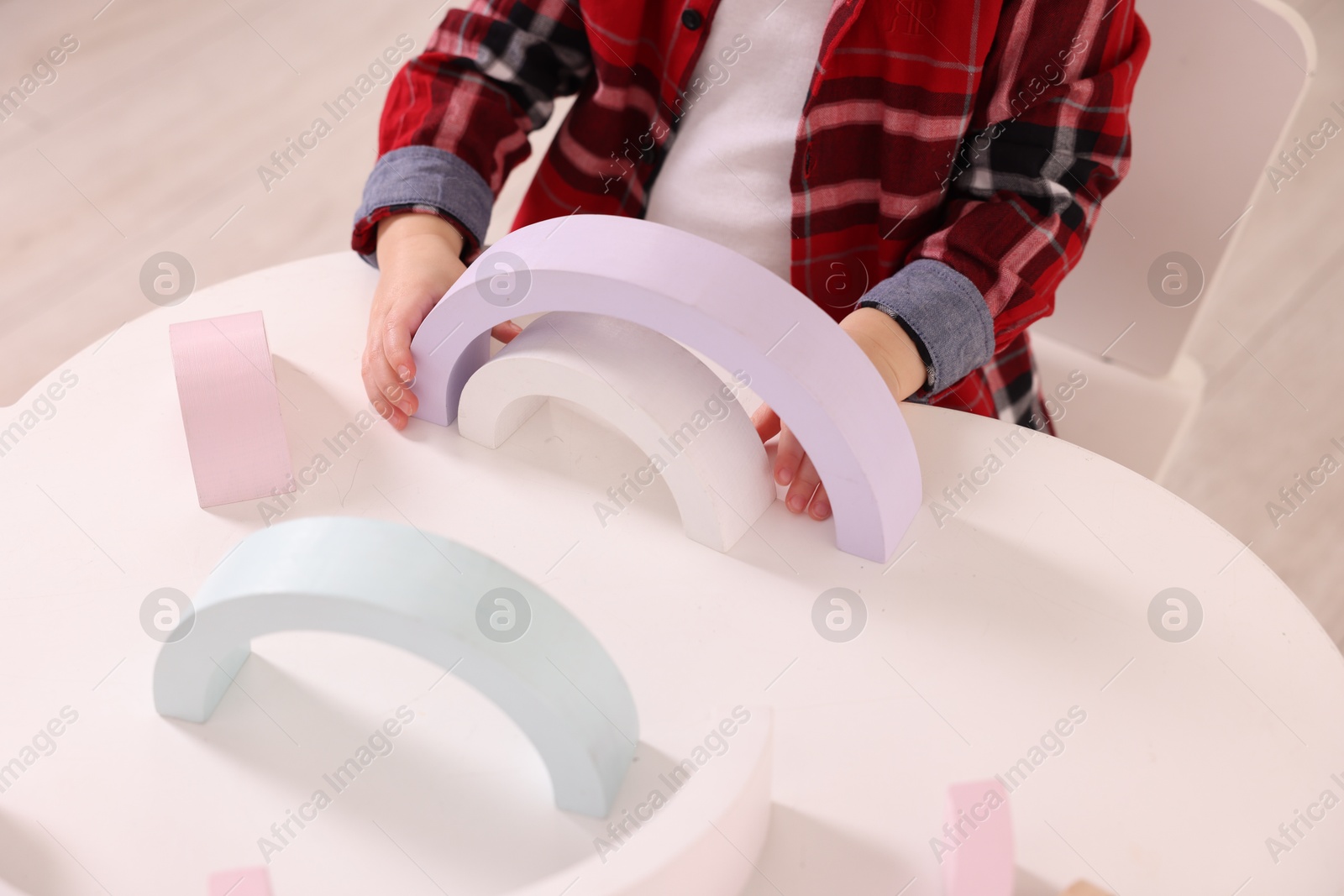 Photo of Motor skills development. Little boy playing with toys at white table indoors, closeup