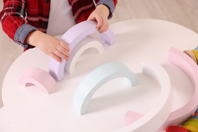 Photo of Motor skills development. Little boy playing with toys at white table indoors, closeup