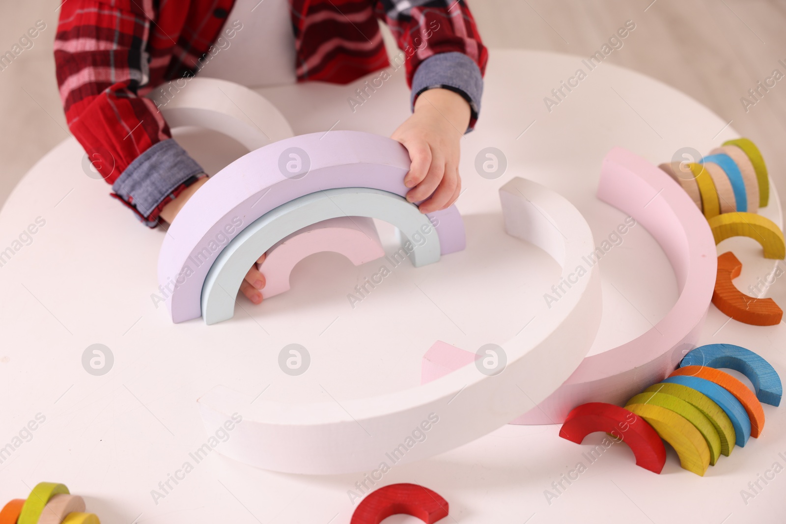 Photo of Motor skills development. Little boy playing with toys at white table indoors, closeup