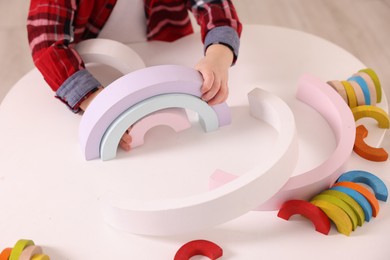 Motor skills development. Little boy playing with toys at white table indoors, closeup