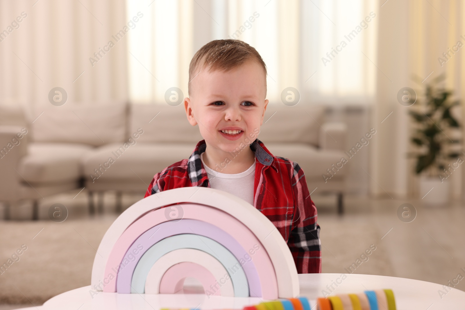 Photo of Motor skills development. Little boy playing with toys at white table indoors