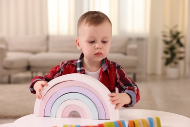 Photo of Motor skills development. Little boy playing with toys at white table indoors