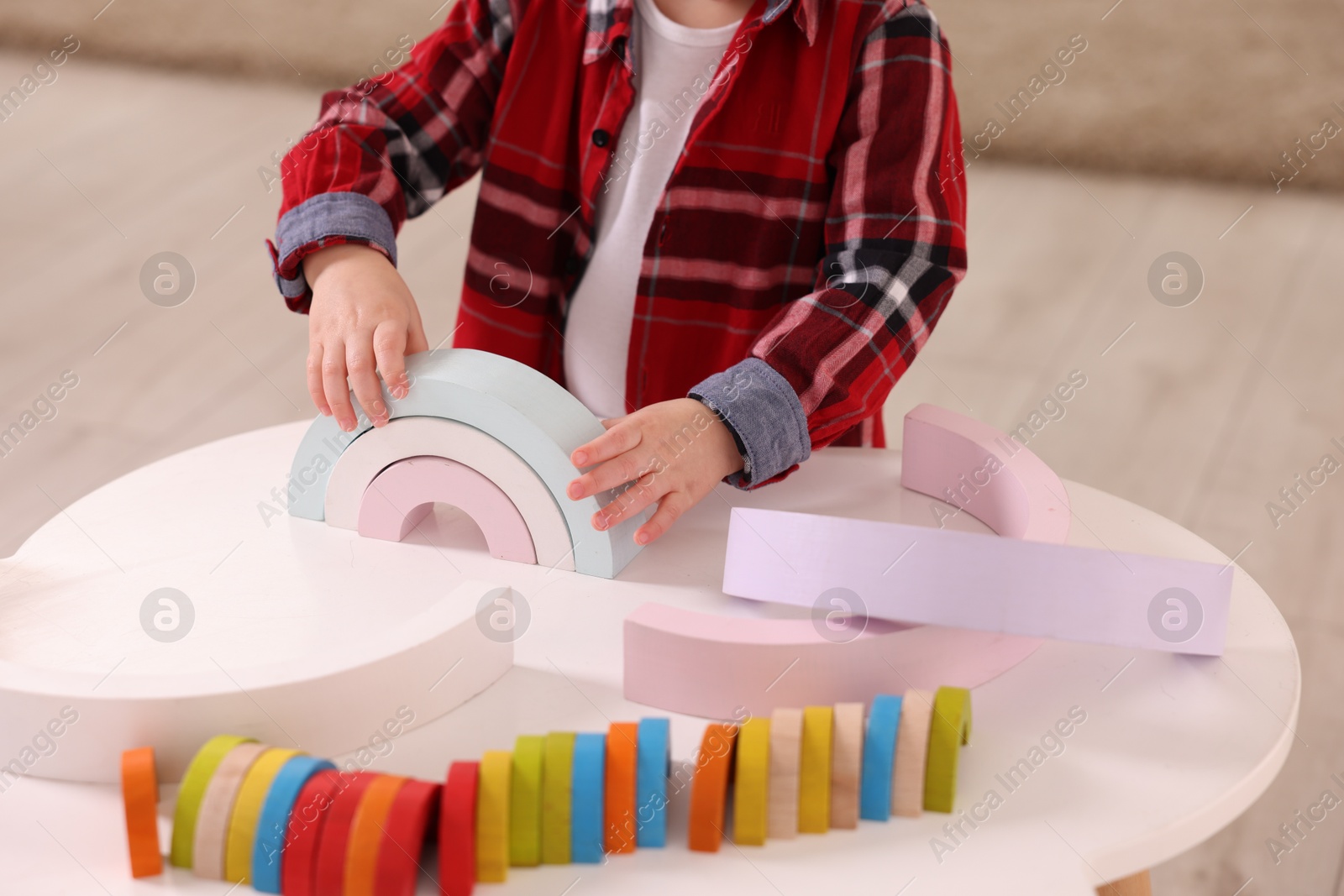 Photo of Motor skills development. Little boy playing with toys at white table indoors, closeup