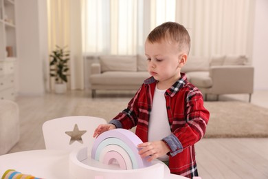 Motor skills development. Little boy playing with toys at white table indoors