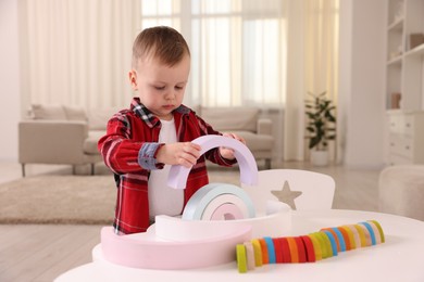 Motor skills development. Little boy playing with toys at white table indoors