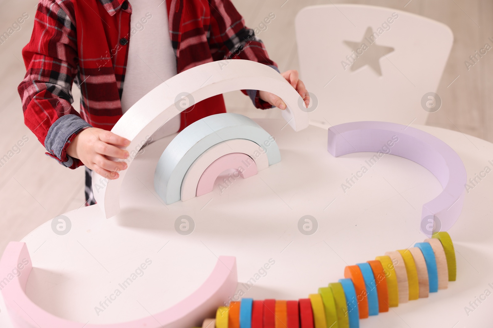 Photo of Motor skills development. Little boy playing with toys at white table indoors, closeup