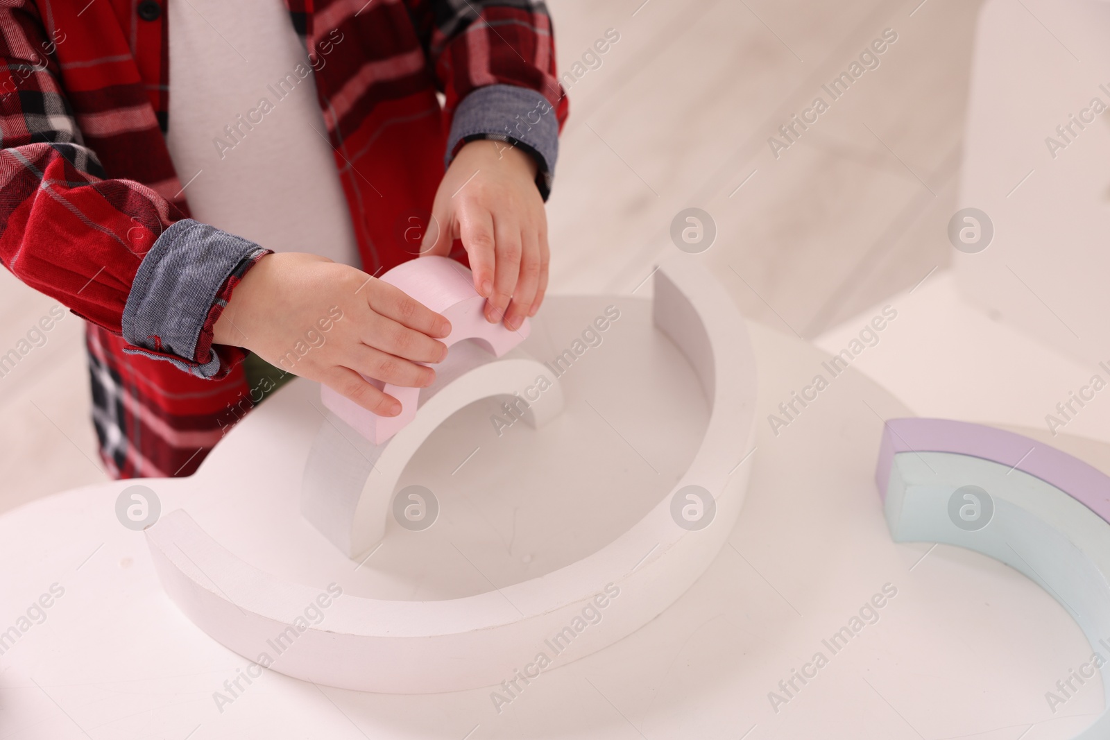 Photo of Motor skills development. Little boy playing with toys at white table indoors, closeup