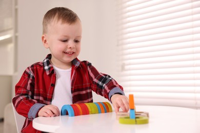 Photo of Motor skills development. Little boy playing with toys at white table indoors, space for text