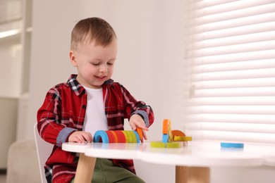 Motor skills development. Little boy playing with toys at white table indoors