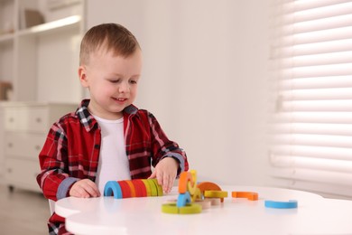 Motor skills development. Little boy playing with toys at white table indoors, space for text