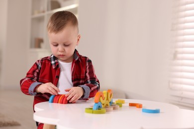 Motor skills development. Little boy playing with toys at white table indoors, space for text