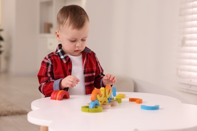 Photo of Motor skills development. Little boy playing with toys at white table indoors, space for text