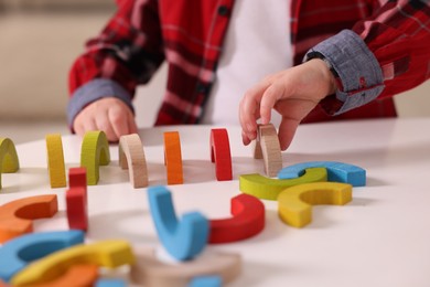 Motor skills development. Little boy playing with toys at white table indoors, closeup