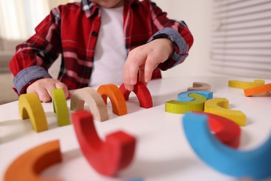 Photo of Motor skills development. Little boy playing with toys at white table indoors, closeup