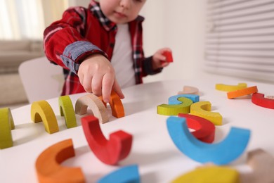 Motor skills development. Little boy playing with toys at white table indoors, selective focus