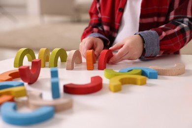 Motor skills development. Little boy playing with toys at white table indoors, closeup