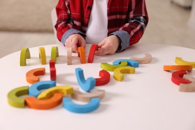 Photo of Motor skills development. Little boy playing with toys at white table indoors, closeup