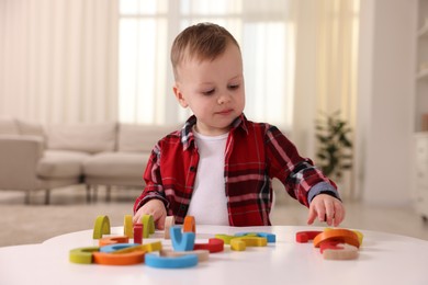 Photo of Motor skills development. Little boy playing with toys at white table indoors