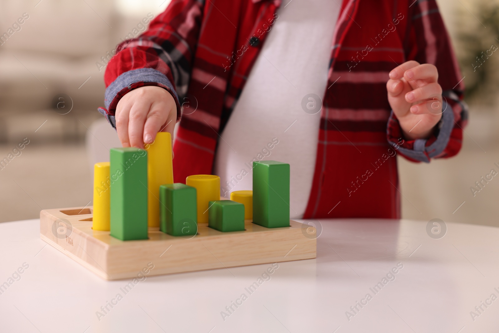 Photo of Motor skills development. Little boy playing with toys at white table indoors, closeup