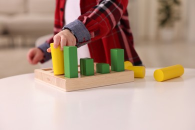 Motor skills development. Little boy playing with toys at white table indoors, closeup