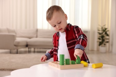 Photo of Motor skills development. Little boy playing with toys at white table indoors