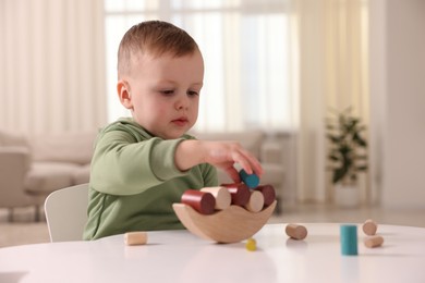 Motor skills development. Little boy playing with balance toy at white table indoors