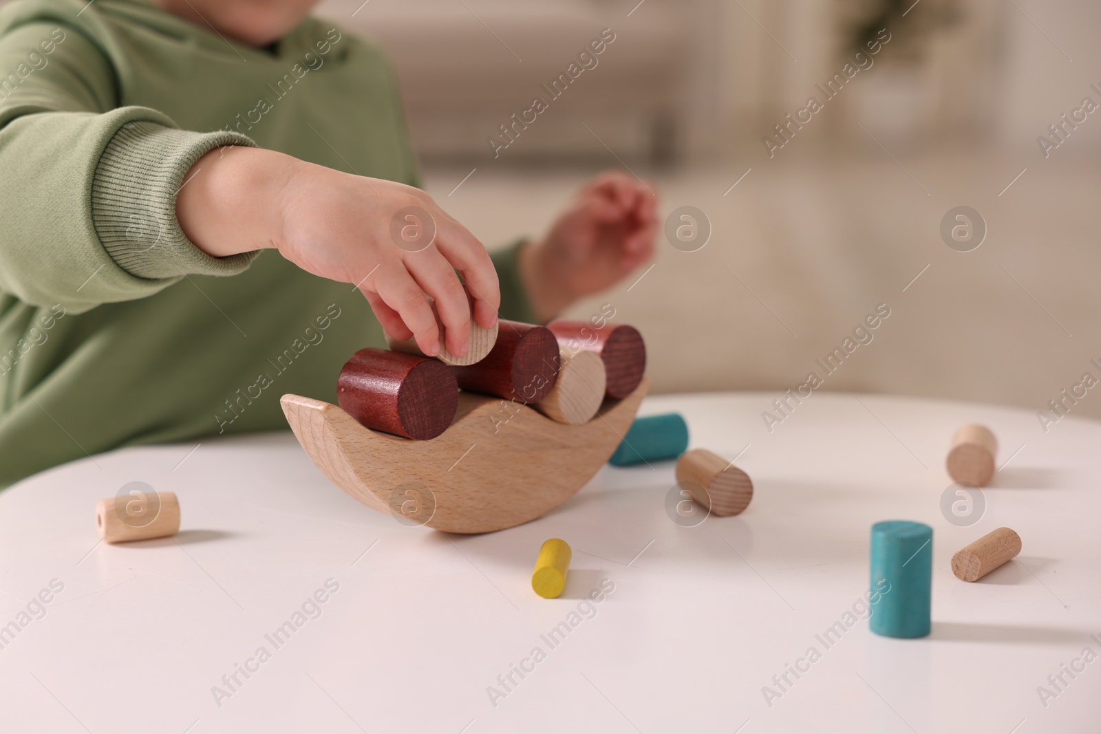 Photo of Motor skills development. Little boy playing with balance toy at white table indoors, closeup