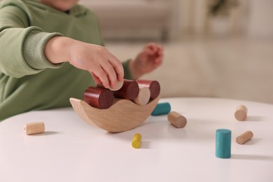 Motor skills development. Little boy playing with balance toy at white table indoors, closeup