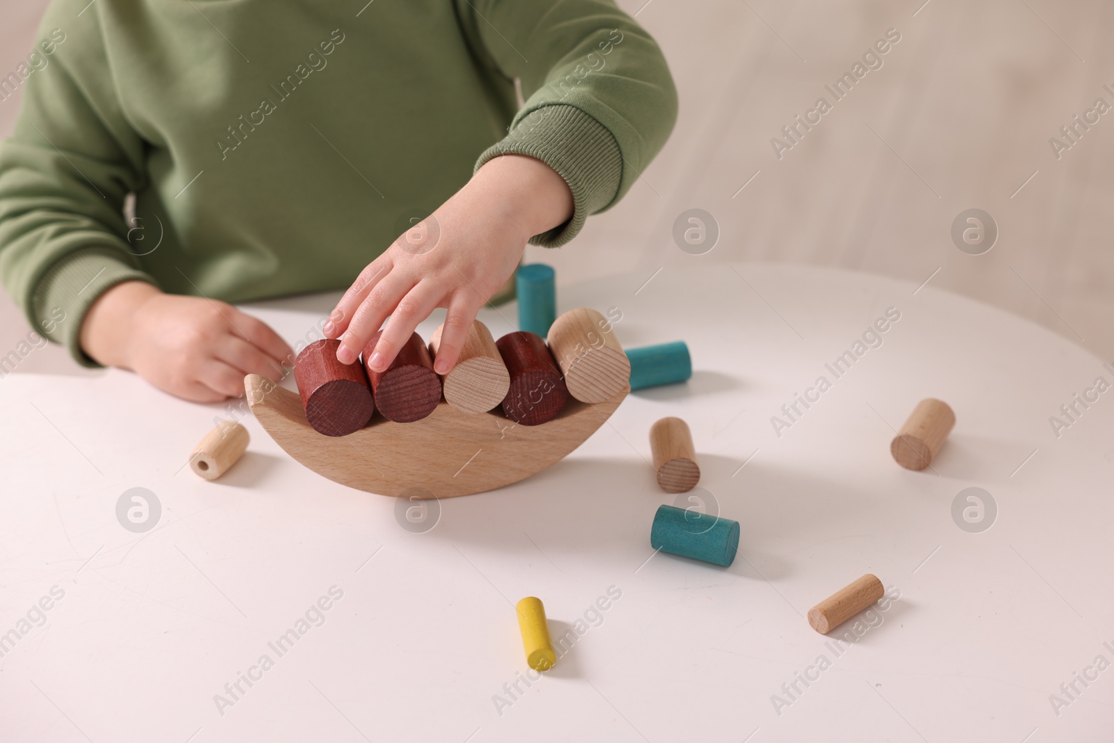 Photo of Motor skills development. Little boy playing with balance toy at white table indoors