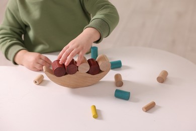 Photo of Motor skills development. Little boy playing with balance toy at white table indoors