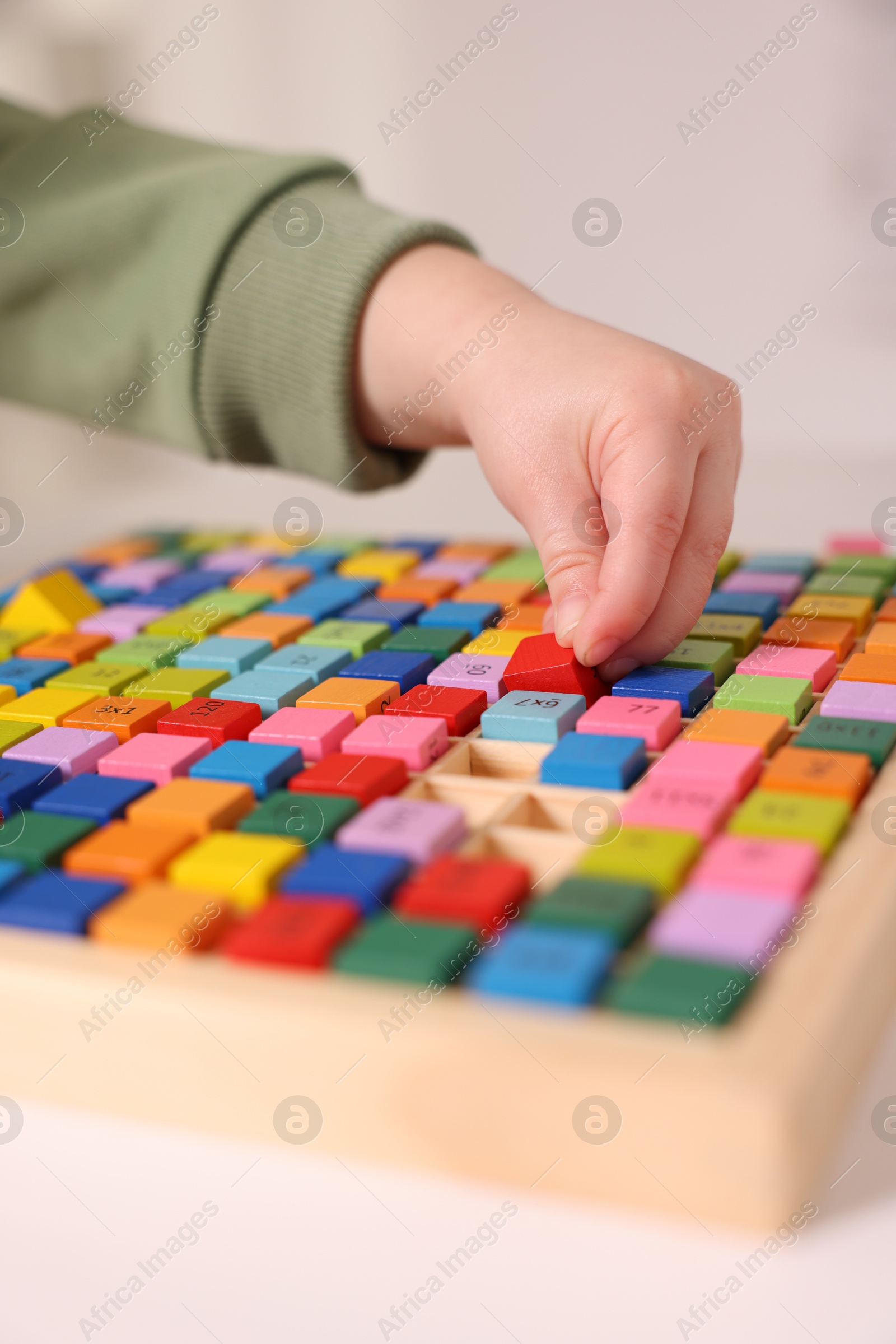 Photo of Motor skills development. Little boy playing with Times table tray indoors, closeup