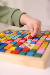 Photo of Motor skills development. Little boy playing with Times table tray indoors, closeup