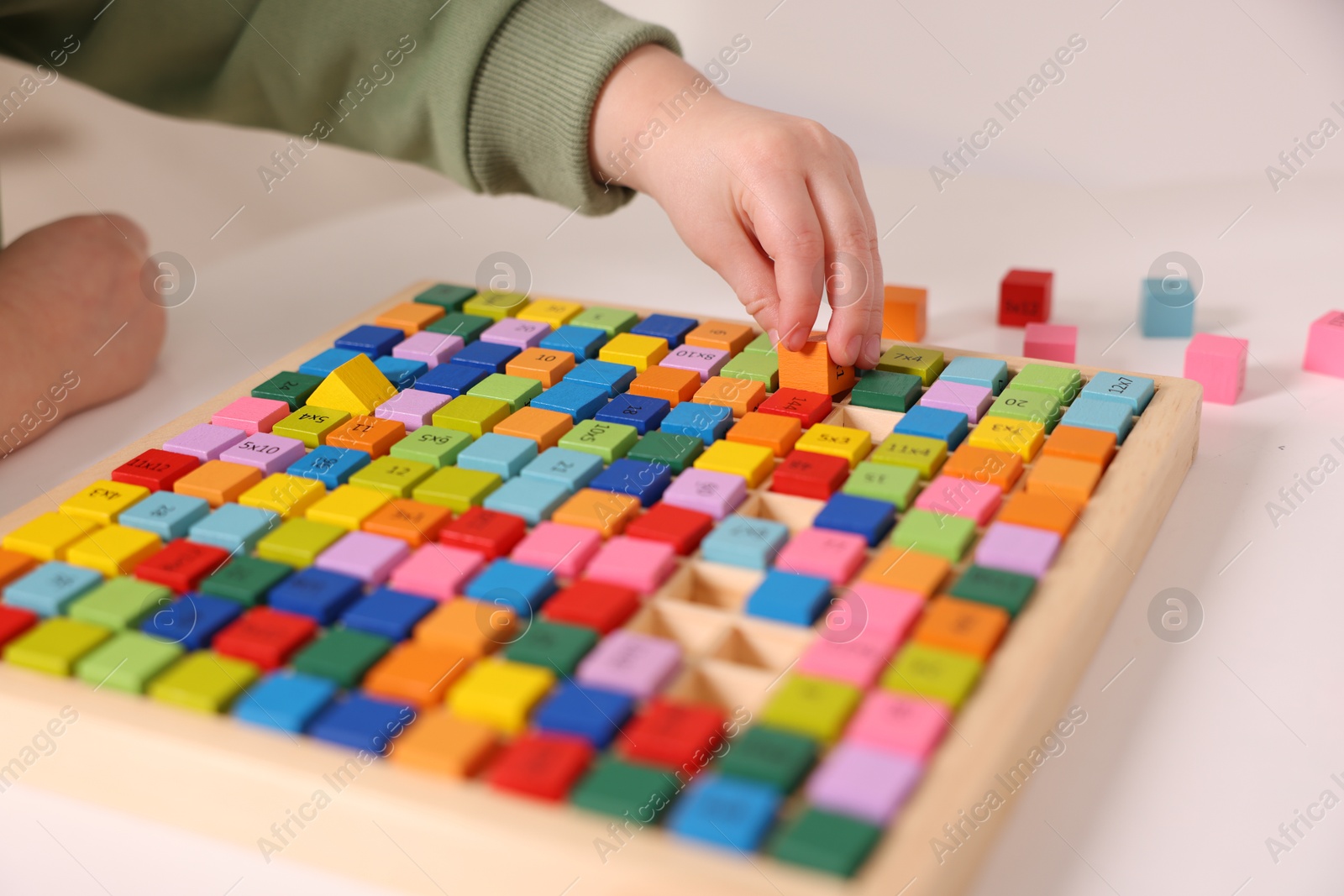 Photo of Motor skills development. Little boy playing with Times table tray indoors, closeup