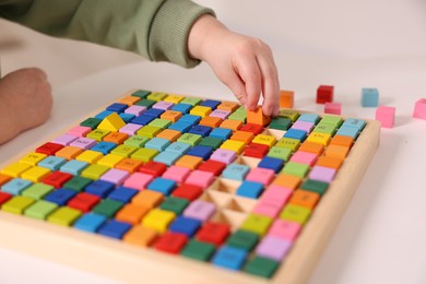 Photo of Motor skills development. Little boy playing with Times table tray indoors, closeup