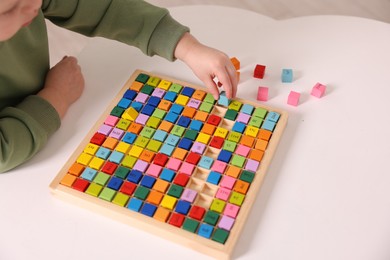 Motor skills development. Little boy playing with Times table tray indoors, closeup